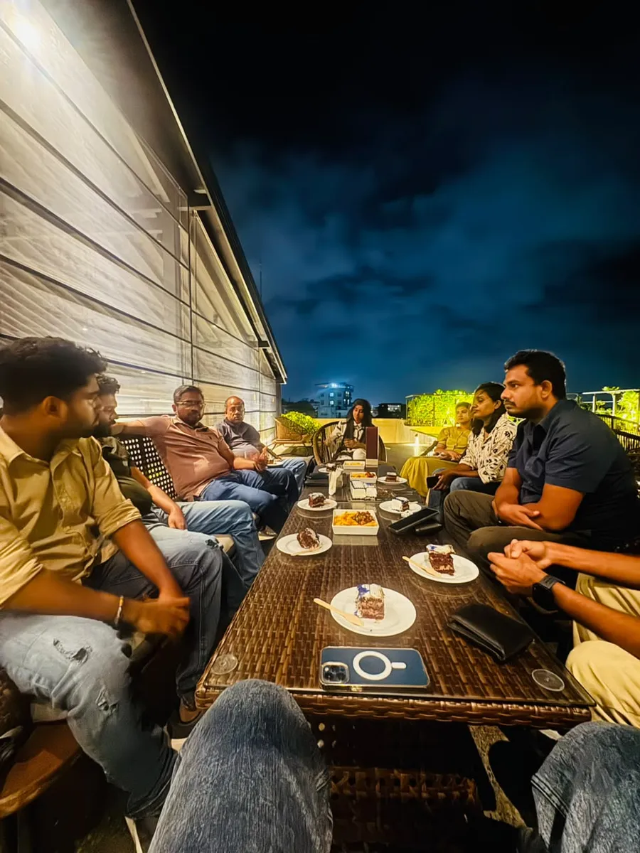 Team members around a table on the rooftop during the evening celebration